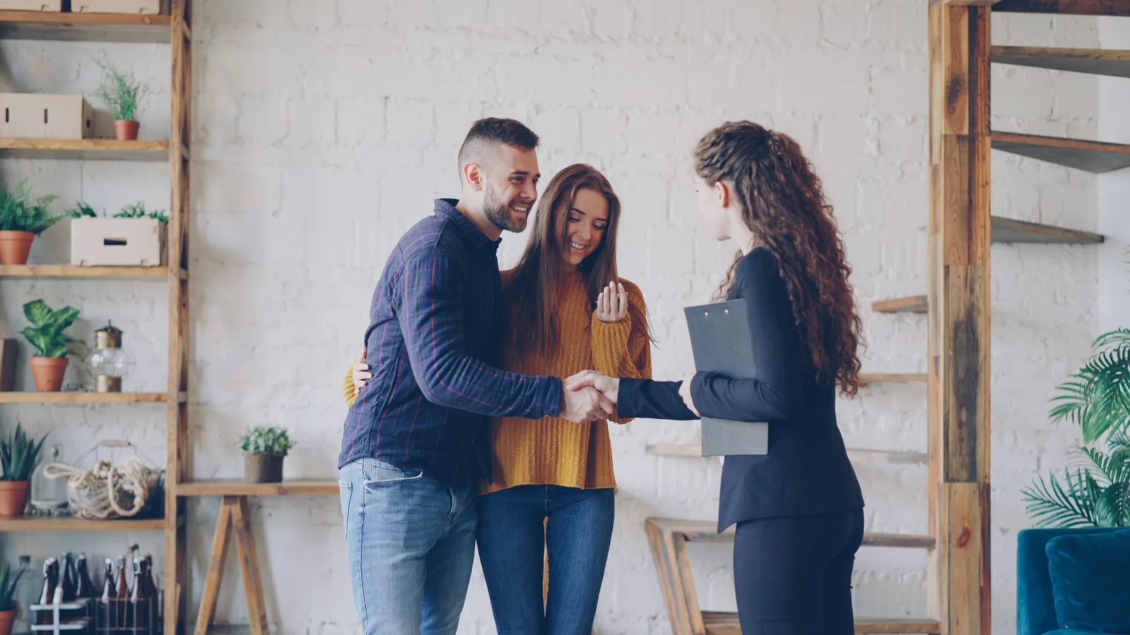 A REVOL agent shaking hands with a couple after a successful home closing