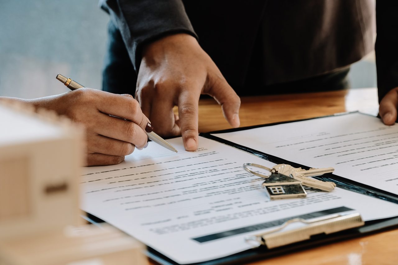 Signing a purchase contract with house keys on the table